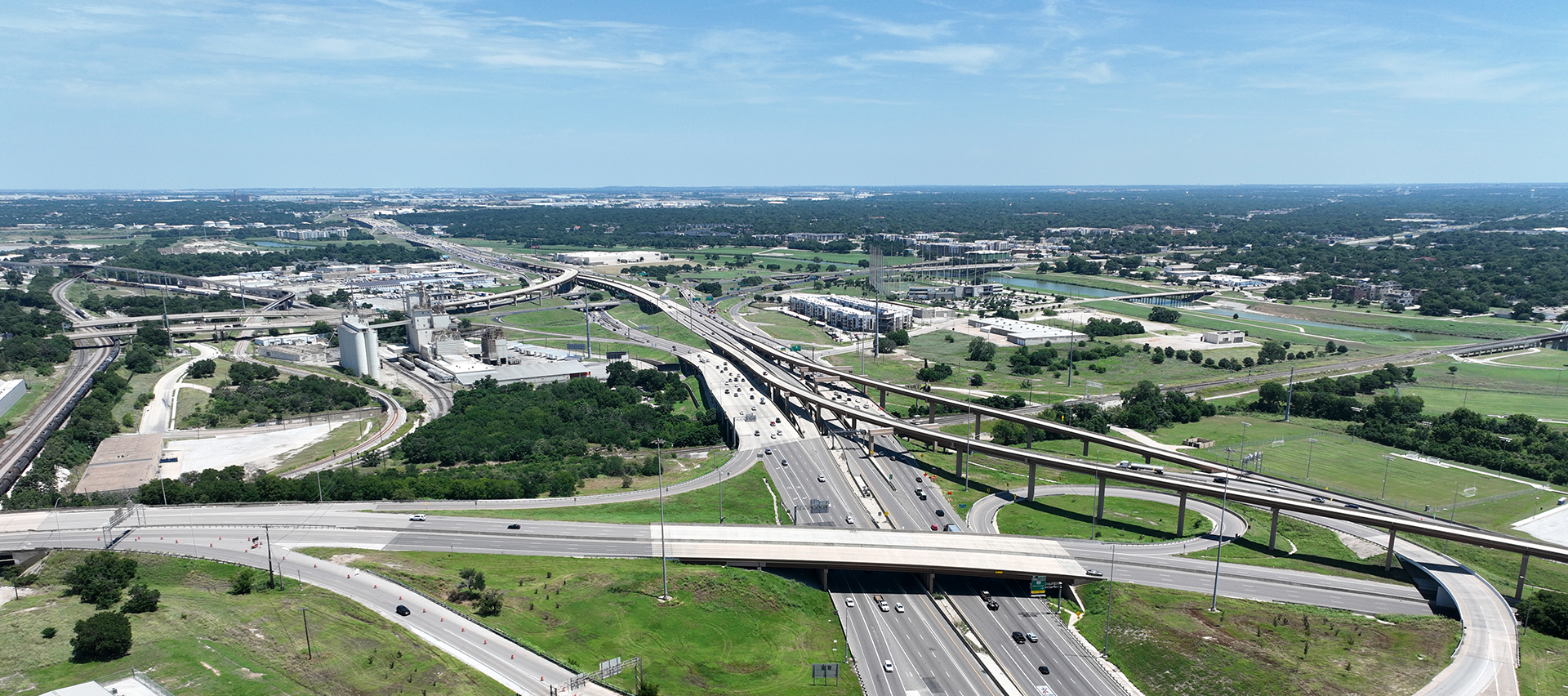 View of a city with highways, buildings, and trees from a drone's point-of-view.